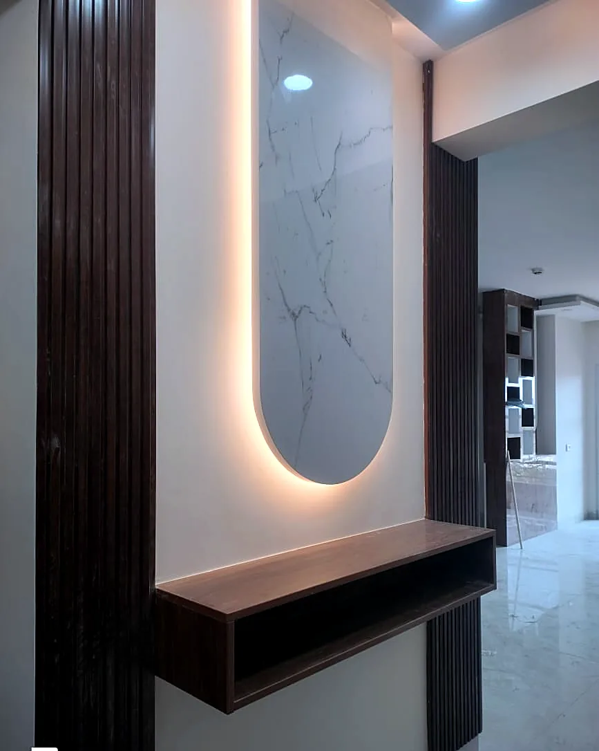 A fluted wood foyer with a backlit marble niche and a floating console